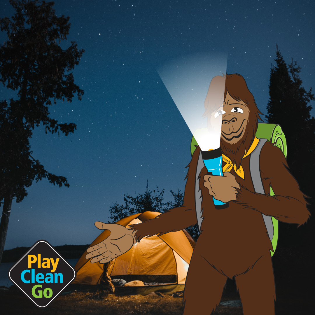 Steward bigfoot with flashlight beaming from under face. Orange tent and starry sky in background.
