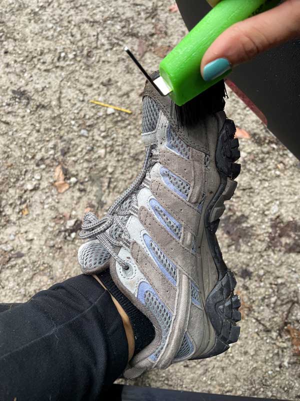 handheld boot brush being used on a Merrell hiking boot